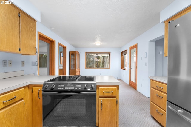 kitchen featuring freestanding refrigerator, electric range, a peninsula, light countertops, and a textured ceiling