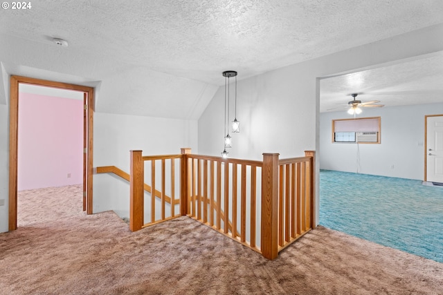 corridor with carpet flooring, an upstairs landing, a textured ceiling, and vaulted ceiling
