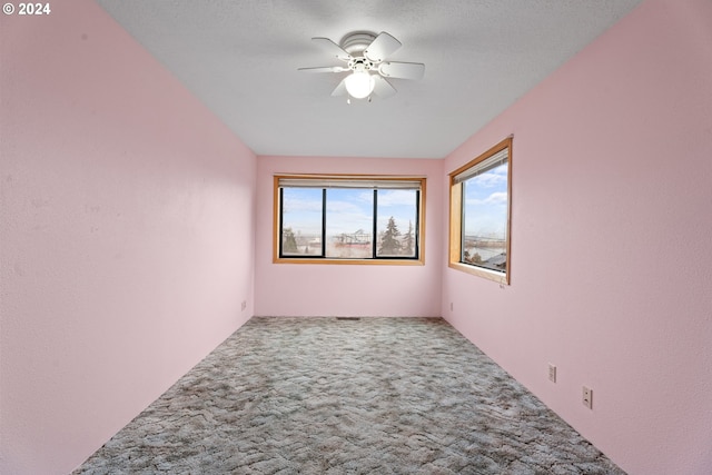 carpeted empty room with a ceiling fan