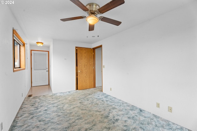 unfurnished bedroom with light colored carpet and a ceiling fan