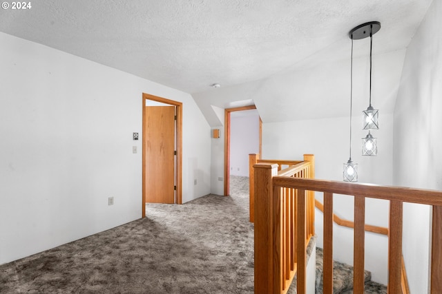 hallway with carpet flooring, an upstairs landing, a textured ceiling, and vaulted ceiling