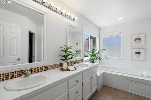 5346 NW Wickiup Way, Portland, OR 97229 - bathroom featuring double vanity, a garden tub, a textured ceiling, tile patterned flooring, and tasteful backsplash
