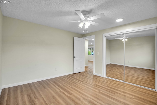 unfurnished bedroom featuring ceiling fan, a textured ceiling, a closet, and light wood-type flooring