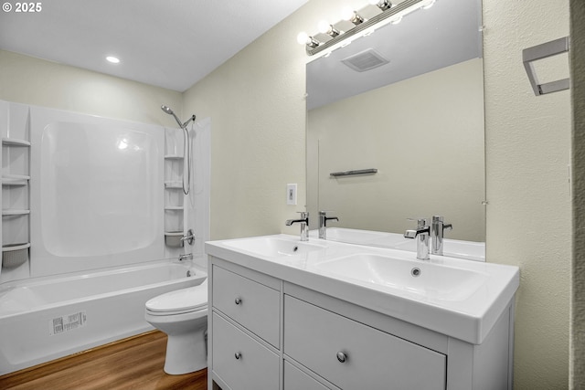 full bathroom featuring wood-type flooring, vanity, washtub / shower combination, and toilet