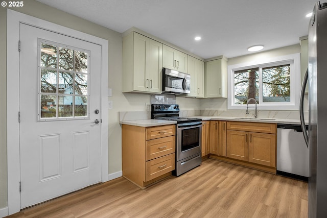 kitchen featuring appliances with stainless steel finishes, sink, and light hardwood / wood-style flooring