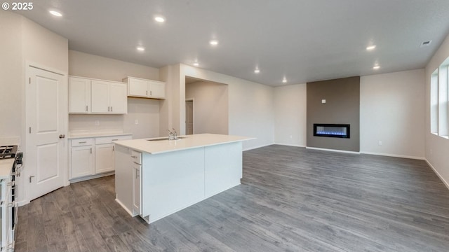 kitchen featuring sink, an island with sink, hardwood / wood-style floors, and white cabinets