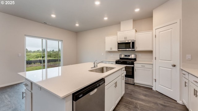 kitchen featuring dark wood-type flooring, sink, white cabinetry, a center island with sink, and appliances with stainless steel finishes