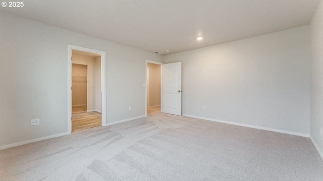 unfurnished bedroom featuring a spacious closet and light carpet