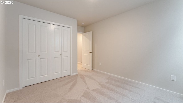 unfurnished bedroom featuring light colored carpet and a closet