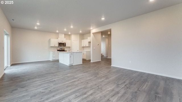 kitchen with white cabinetry, appliances with stainless steel finishes, a center island, and hardwood / wood-style floors