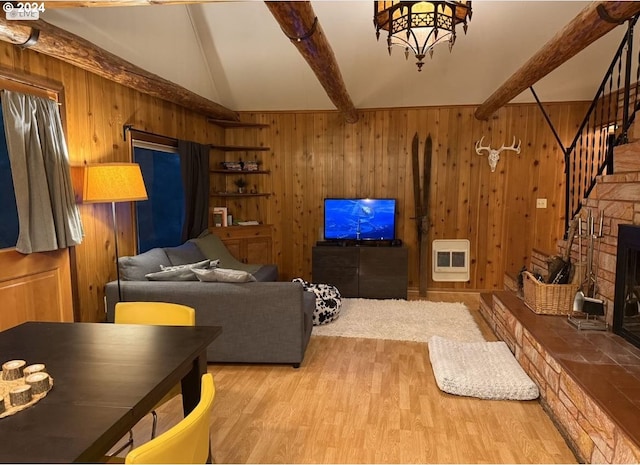 living room featuring wooden walls, beam ceiling, heating unit, and light hardwood / wood-style flooring