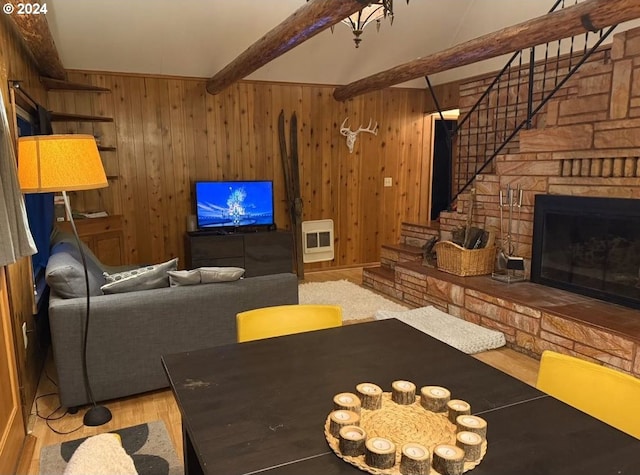 unfurnished living room featuring beamed ceiling, wooden walls, a fireplace, and light hardwood / wood-style flooring