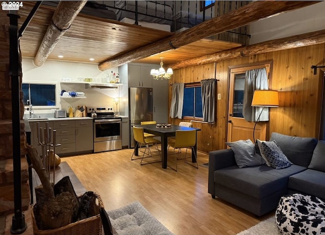 living room with an inviting chandelier, wooden walls, beamed ceiling, wooden ceiling, and light wood-type flooring