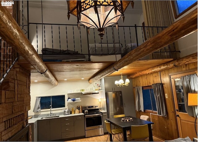 kitchen featuring sink, an inviting chandelier, stainless steel range with electric stovetop, beam ceiling, and a high ceiling