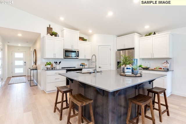 kitchen featuring appliances with stainless steel finishes, a breakfast bar area, a sink, and white cabinetry