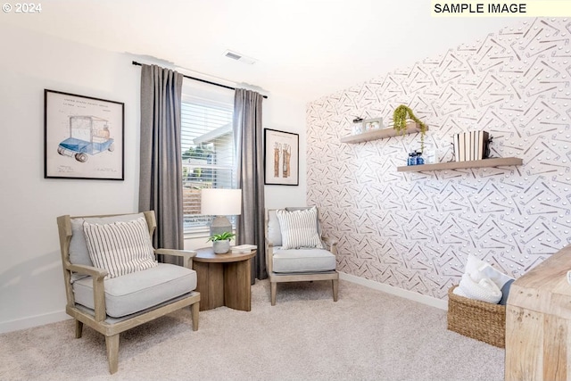 living area featuring carpet floors, wallpapered walls, an accent wall, and baseboards