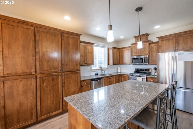 kitchen with a kitchen bar, a center island, stone counters, and appliances with stainless steel finishes