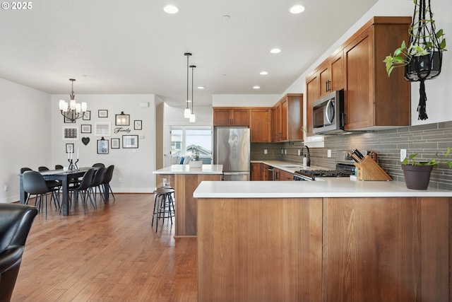 29176 SW Costa Cir E, Wilsonville, OR 97070 - kitchen featuring stainless steel appliances, brown cabinets, a chandelier, light countertops, and decorative backsplash