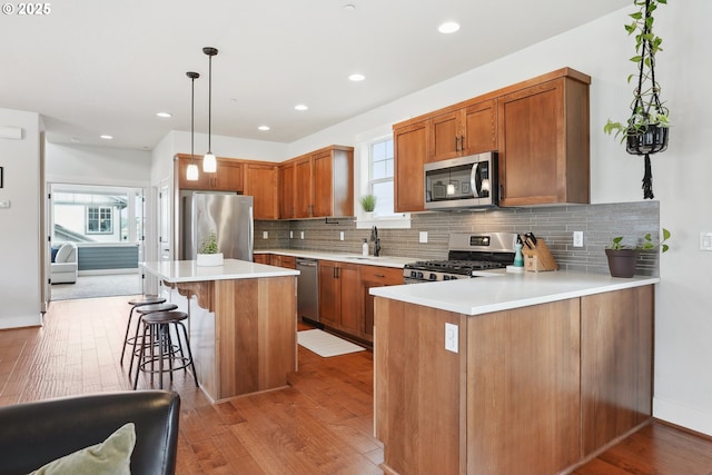 29176 SW Costa Cir E, Wilsonville, OR 97070 - kitchen featuring appliances with stainless steel finishes, a breakfast bar area, light wood finished floors, backsplash, and recessed lighting