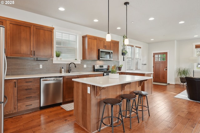 29176 SW Costa Cir E, Wilsonville, OR 97070 - kitchen with stainless steel appliances, hardwood / wood-style flooring, brown cabinetry, a sink, and a breakfast bar