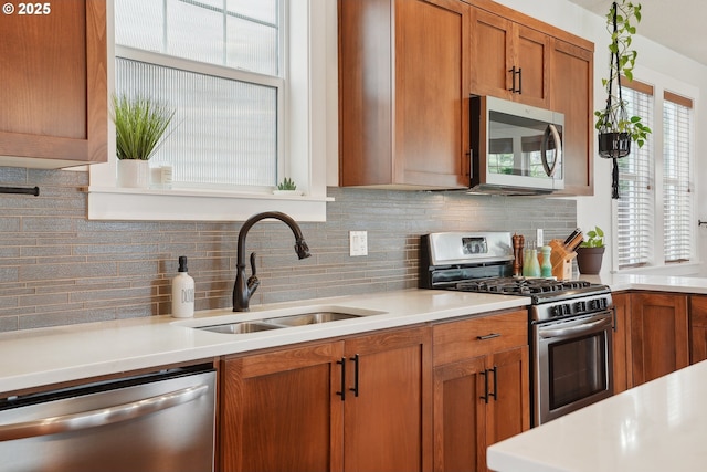 29176 SW Costa Cir E, Wilsonville, OR 97070 - kitchen with stainless steel appliances, a sink, tasteful backsplash, brown cabinetry, and light countertops