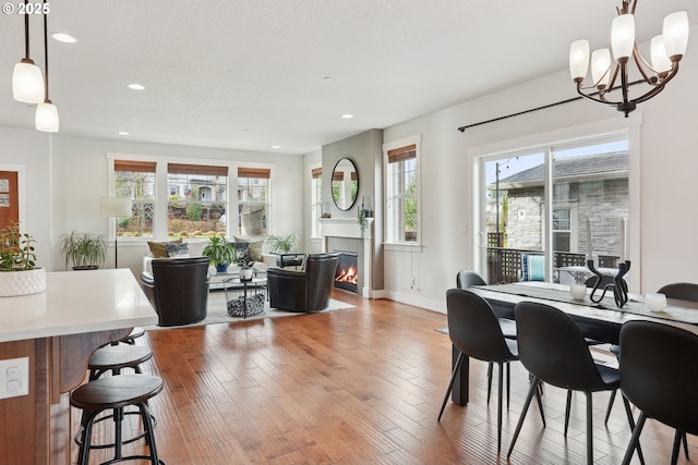 29176 SW Costa Cir E, Wilsonville, OR 97070 - dining space featuring recessed lighting, a chandelier, light wood finished floors, a glass covered fireplace, and baseboards