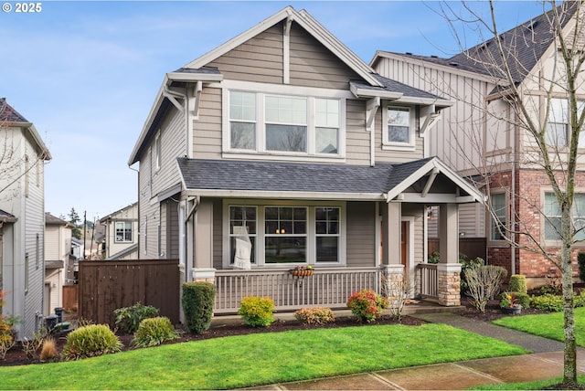 view of front of house with covered porch, a front yard, fence, and roof with shingles