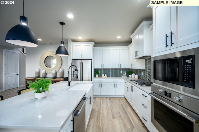 4304 NE 188th St Lot 331, Vancouver, WA 98686 - kitchen with appliances with stainless steel finishes, a kitchen island with sink, backsplash, white cabinets, and light wood finished floors