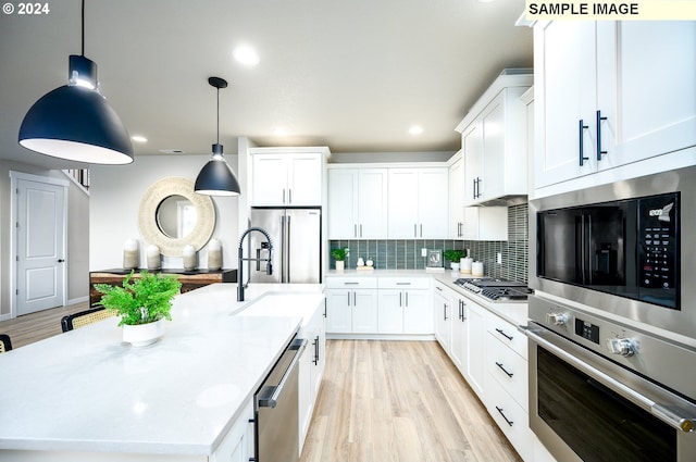 4304 NE 188th St Lot 331, Vancouver, WA 98686 - kitchen featuring stainless steel appliances, an island with sink, decorative backsplash, light wood-style flooring, and white cabinets