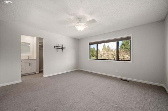 unfurnished bedroom with a spacious closet, carpet flooring, visible vents, and baseboards