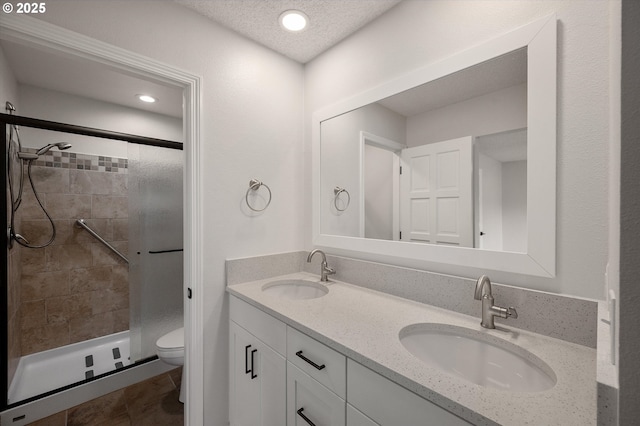 full bathroom featuring a stall shower, a sink, toilet, and double vanity