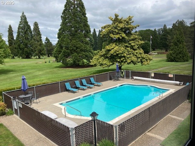 community pool featuring a yard, a patio, and fence