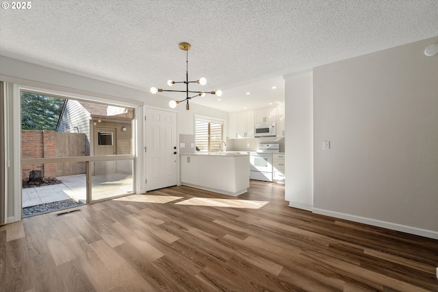 unfurnished living room with a textured ceiling, baseboards, and wood finished floors