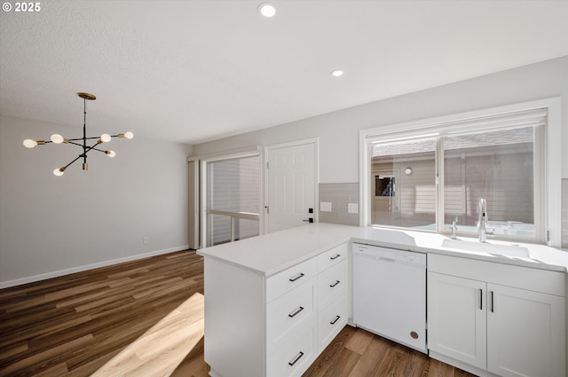 kitchen featuring white dishwasher, dark wood-type flooring, a sink, and light countertops