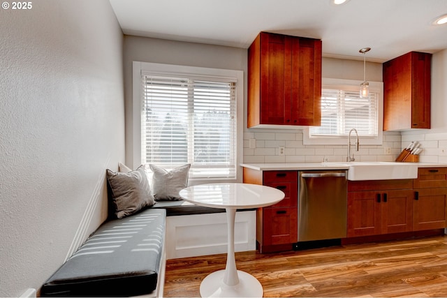 kitchen featuring dishwasher, light wood finished floors, a sink, and decorative backsplash