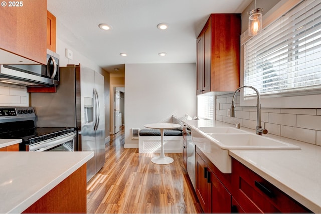 kitchen with light countertops, stainless steel appliances, light wood-type flooring, a sink, and recessed lighting