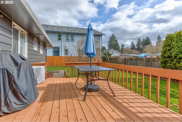 wooden deck featuring outdoor dining area, fence, and a lawn