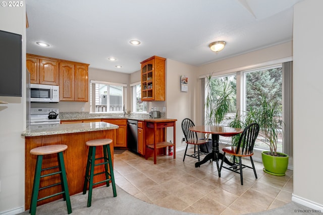 24788 E Mckenzie Valley Ct, Welches, OR 97067 - kitchen with white appliances, glass insert cabinets, brown cabinetry, a peninsula, and a breakfast bar