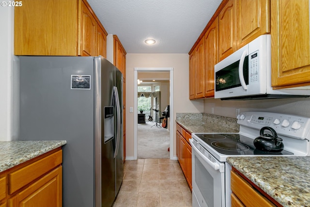 24788 E Mckenzie Valley Ct, Welches, OR 97067 - kitchen featuring light tile patterned floors, white appliances, brown cabinetry, light stone counters, and light carpet