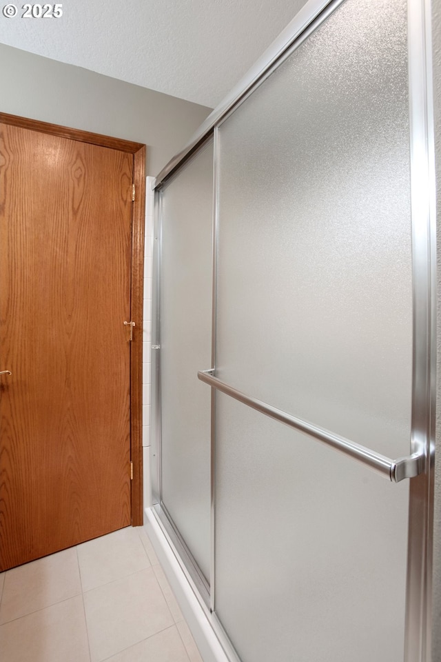 bathroom featuring a shower with shower door, tile patterned floors, and a textured ceiling