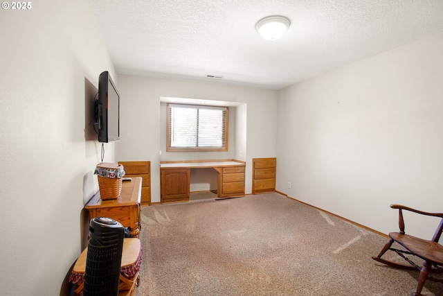 carpeted home office with built in desk and a textured ceiling