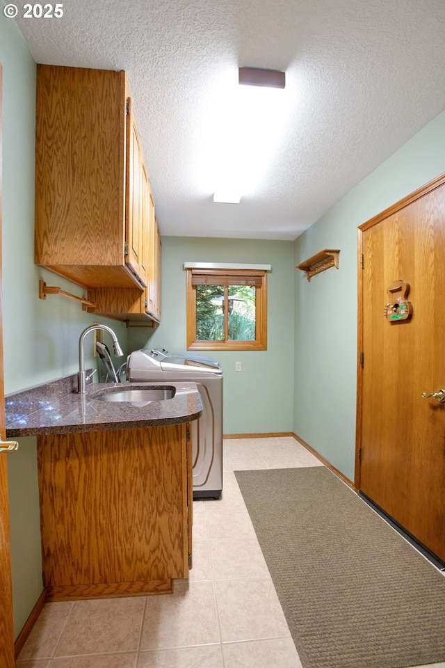 laundry area with sink, washer and clothes dryer, cabinets, a textured ceiling, and light tile patterned flooring