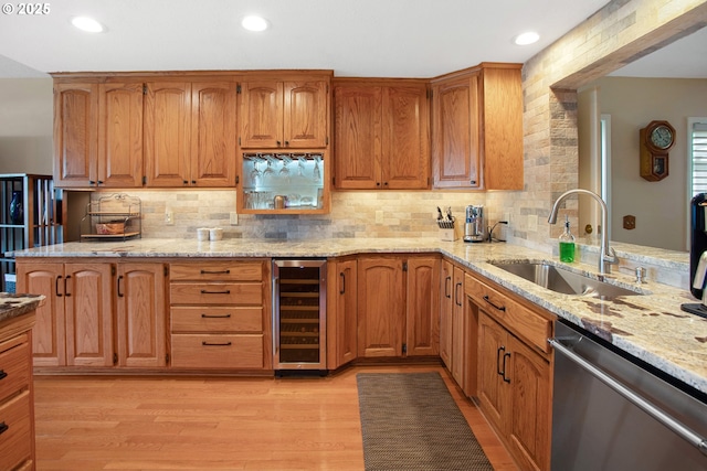 kitchen with sink, light stone counters, light hardwood / wood-style floors, stainless steel dishwasher, and beverage cooler