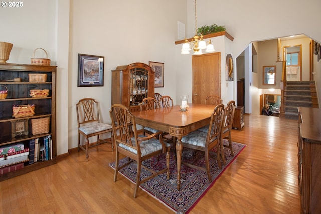 dining room with a towering ceiling, an inviting chandelier, and light hardwood / wood-style flooring