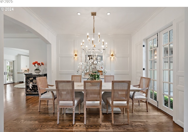 dining space with ornamental molding, arched walkways, and a decorative wall