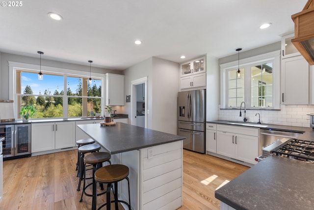 kitchen with beverage cooler, dark countertops, stainless steel fridge, and a sink
