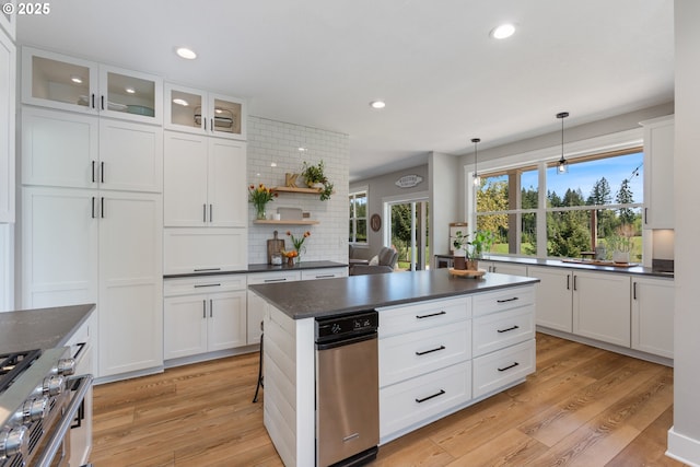 kitchen with high end stainless steel range, dark countertops, recessed lighting, light wood finished floors, and backsplash