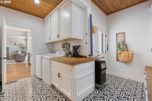 clothes washing area with washing machine and clothes dryer, cabinet space, tile patterned flooring, baseboards, and wood ceiling