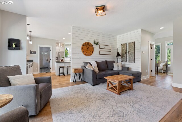 living room featuring light wood-type flooring, recessed lighting, and wooden walls