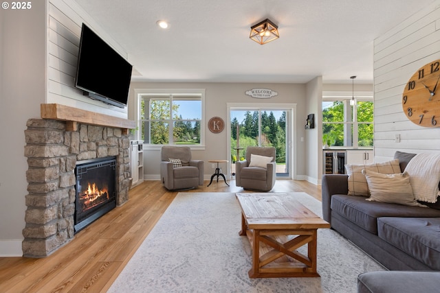 living room featuring wooden walls, baseboards, light wood-style flooring, and a fireplace